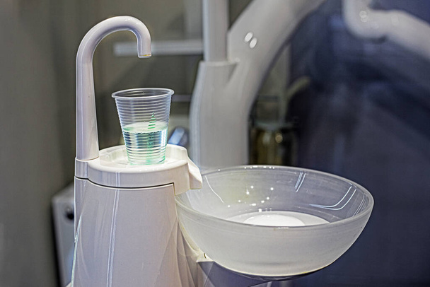 Flüssigkeitsglas, das zum Spülen der Zähne in einer Zahnarztpraxis verwendet wird, betont die Zahnpflege und -behandlung - Foto, Bild