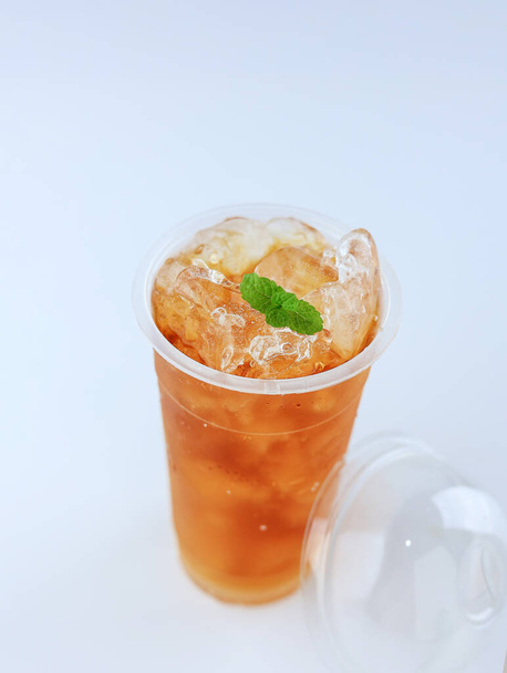 Thé glacé sur tasse en plastique avec feuille de menthe, isolé sur blanc - Photo, image