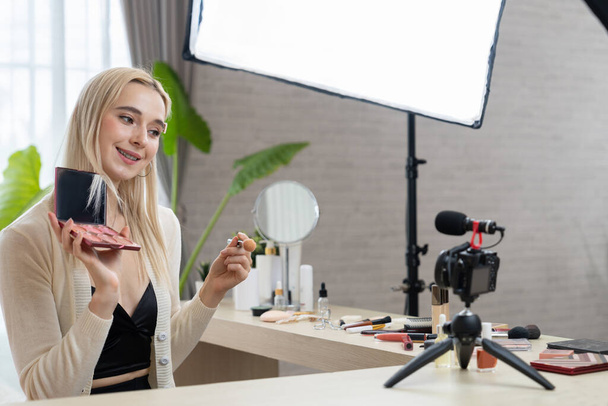 Young woman making beauty and cosmetic tutorial video content for social media. Beauty blogger smiles to camera while showing how to beauty care to audience or followers. Blithe - Photo, Image