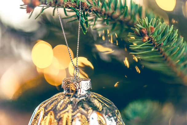 Bola de Navidad brillante plateada en una rama de árbol de Navidad, de cerca. Fondo de Navidad con una bola de Navidad en un primer plano de la rama. - Foto, Imagen