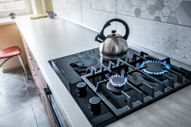 Steel kettle with whistle on modern induction and burning gas stove. Food and drink theme - Photo, Image