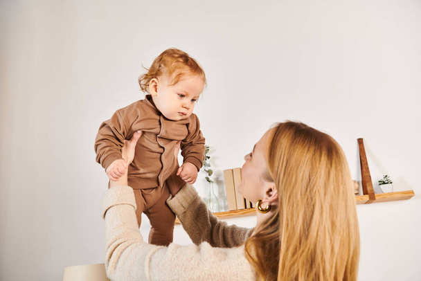 radosna młoda kobieta bawiąca się i bawiąca z małym synkiem malucha w domu, szczęśliwe macierzyństwo - Zdjęcie, obraz