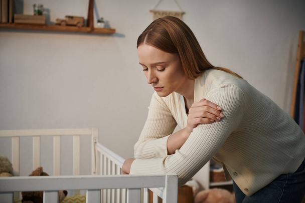 depressed woman standing near crib with soft toys in bleak nursery room at home, frustration - Photo, Image