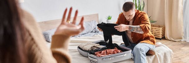 欲求不満 タトゥー 男 パッキング スーツケース 妻の近くで 自宅の寝室で喧嘩, 水平なバナー - 写真・画像