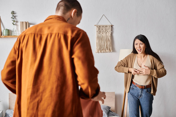 ärtynyt aasialainen nainen riitelee aviomies seisoo vaatteet makuuhuoneessa, perheen konflikti - Valokuva, kuva