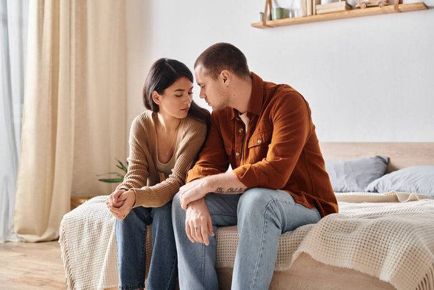 joven y triste pareja interracial sentado y hablando en la cama en casa, dificultades de relación - Foto, Imagen