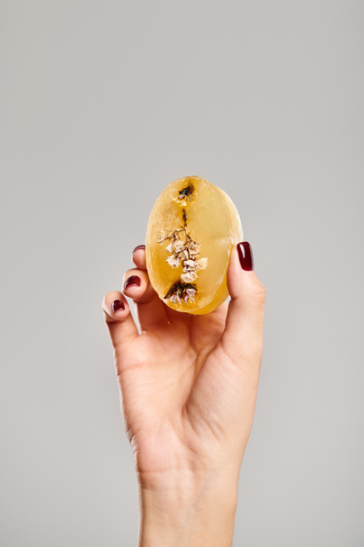 morceau de savon naturel orange avec des décorations en main de jeune femme inconnue sur fond gris - Photo, image