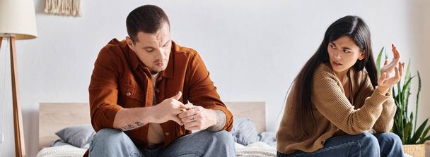 zdenerwowana azjatycka kobieta siedzi i kłóci się z mężem w sypialni w domu, baner poziomy - Zdjęcie, obraz