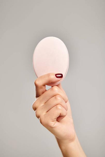 pezzo ovale di sapone naturale in mano di modello femminile sconosciuto con smalto su sfondo grigio - Foto, immagini