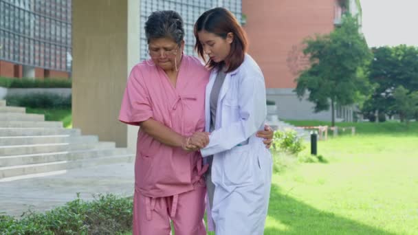 高齢のアジア人女性が理学療法をし,医師と一緒に庭を歩いている. 介護者・貯蓄・高齢者健康保険,ヘルスケアによる幸せな退職のコンセプト - 映像、動画