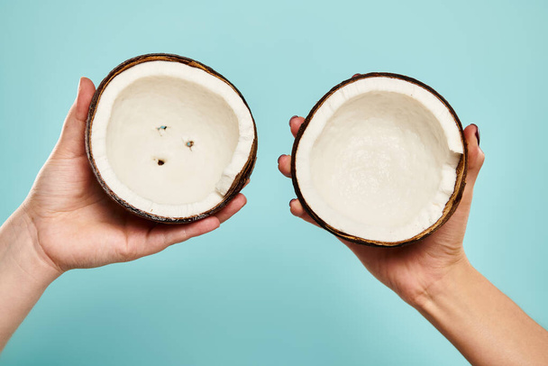 objekt fotografie gurmánského čerstvého kokosu v rukou mladé neznámé ženské modelky na modrém pozadí - Fotografie, Obrázek