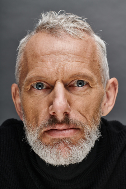 portrait of handsome bearded mature male model in fashionable black turtleneck looking at camera - Photo, Image