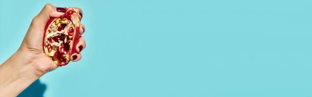 άγνωστο θηλυκό μοντέλο πιέζοντας φρέσκο νόστιμο ρόδι σε μπλε ζωντανό φόντο, banner - Φωτογραφία, εικόνα