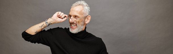 cheerful handsome mature male model with glasses and beard in black turtleneck looking away, banner - Photo, Image