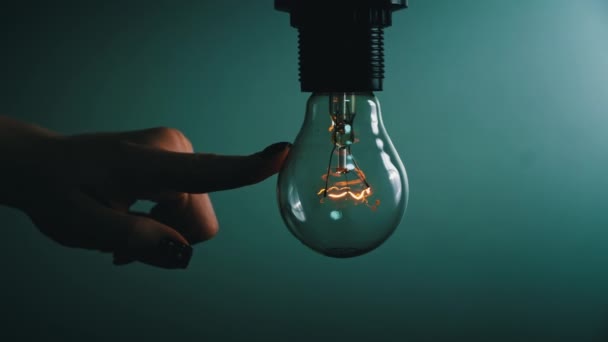 Light bulb turns on and goes out at the touch of a persons hand in the dark. Slow turning on and off of a tungsten light bulb. Filament of a blinking vintage light bulb. Energy, electricity, light - Filmmaterial, Video
