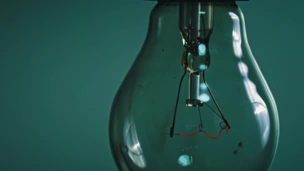 Light bulb flashes on a blue background in the dark. Slow turning on and off of a tungsten light bulb. Filament of a blinking vintage light bulb. Energy, electricity, light, life. - Filmati, video