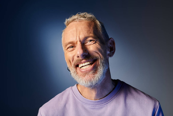 alegre atractivo hombre maduro con barba gris y atuendo casual de moda sonriendo felizmente a la cámara - Foto, imagen