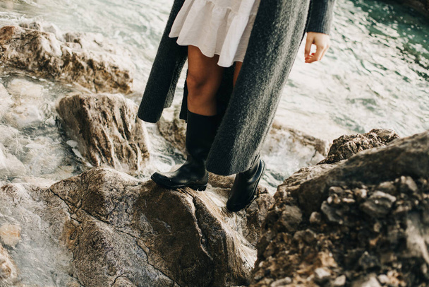 Girl in rubber boots on the rocks by the sea. Selective focus. - Photo, Image