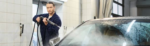 красивий спеціаліст у блакитній формі з зібраним автомобілем для миття волосся в гаражі, банер - Фото, зображення