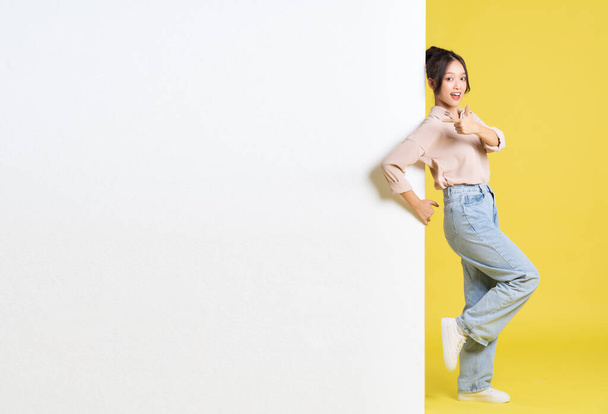зображення азіатської дівчини, що стоїть і позує з рекламним щитом - Фото, зображення