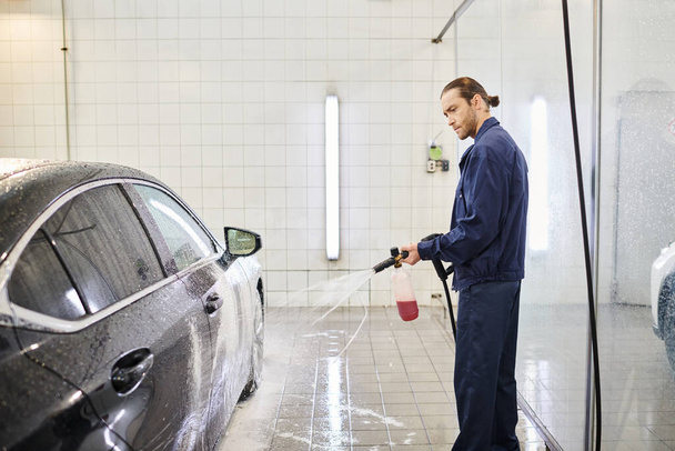 atrakcyjny dedykowany specjalista w niebieskim mundurze z zebranymi włosami za pomocą mydła do mycia samochodów - Zdjęcie, obraz