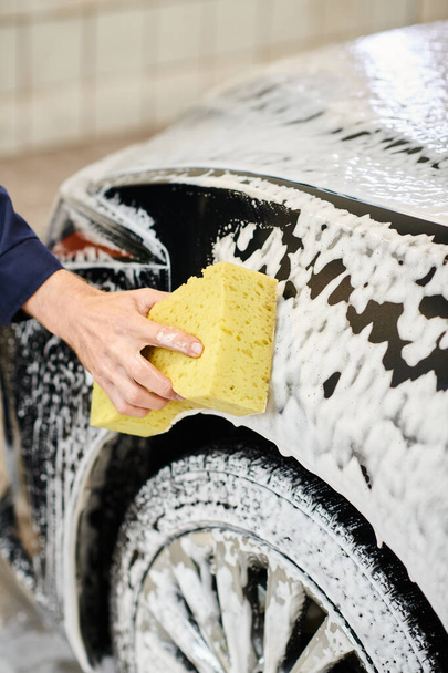 обрізаний вид важкої роботи спеціаліст з рівномірного миття чорного автомобіля за допомогою губки - Фото, зображення