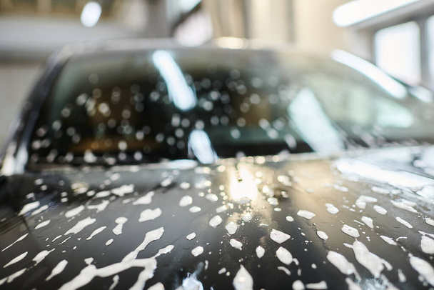 объект фото мыльного капюшона черного современного автомобиля во время детального обслуживания автомобиля в гараже - Фото, изображение
