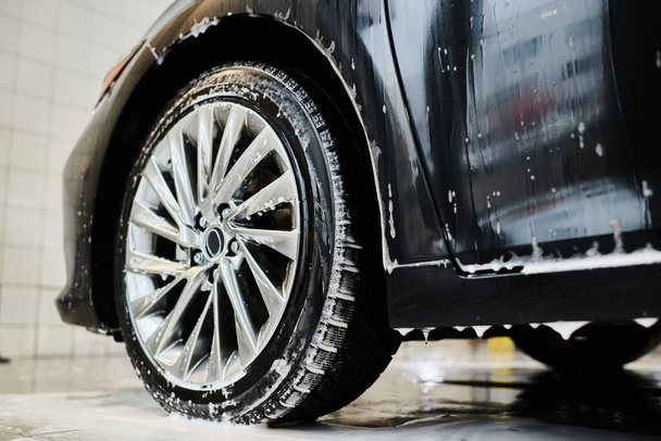 oggetto foto di brillante stanco di nero moderno auto coperto con sapone durante il servizio di auto dettaglio - Foto, immagini