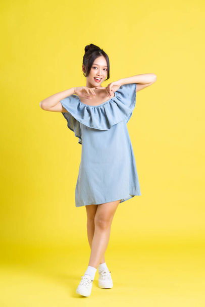 portrait of Asian woman in skirt posing on yellow background - Photo, Image