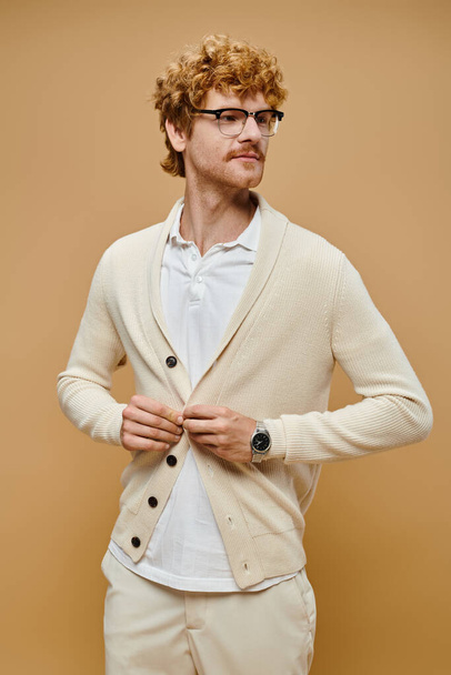 giovane modello maschile alla moda in occhiali abbottonatura cardigan su sfondo beige, vecchio denaro moda - Foto, immagini
