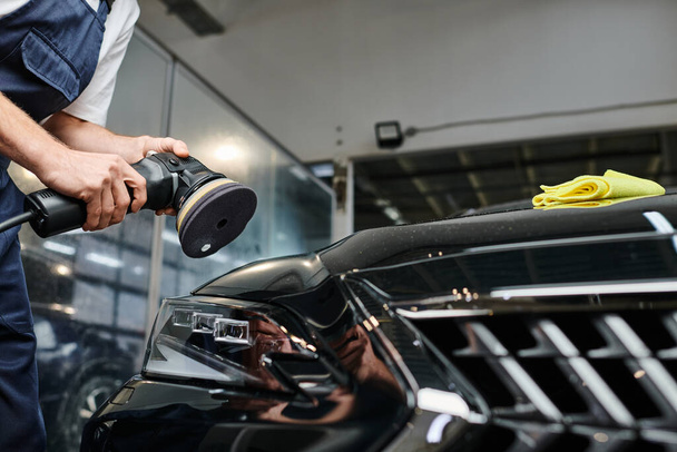 cropped view of professional hard working specialist using polishing machine on black modern car - Photo, Image