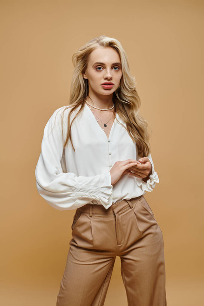 junge blonde Frau in klassischer, lässiger Kleidung, die auf beige, zeitlose Mode in die Kamera blickt - Foto, Bild