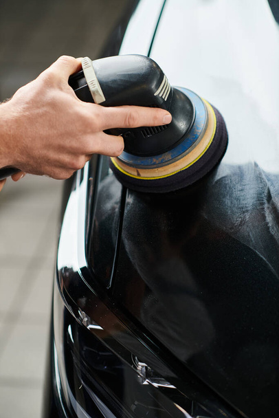 обрезанный вид трудолюбивого военнослужащего с помощью тщательно полировальной машины на черном современном автомобиле - Фото, изображение