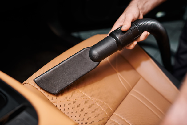 обрізаний вид на працівника з використанням ручного пилососа на сидінні в машині в гаражі - Фото, зображення