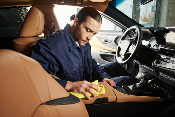 attraente serviceman devoto in uniforme blu con raccolta auto per la pulizia dei capelli con straccio giallo - Foto, immagini