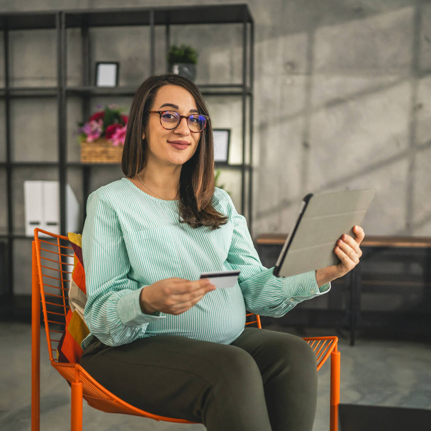 Terhes nő csinál online vásárlás hold hitelkártya ülni otthon - Fotó, kép