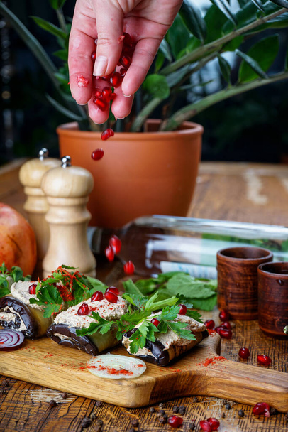 Грузинская закуска баклажанов в рулонах с начинкой, посыпанной семенами граната на стол с чачей и растением - Фото, изображение