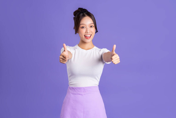 Portrait d'une belle femme asiatique posant sur un fond violet - Photo, image