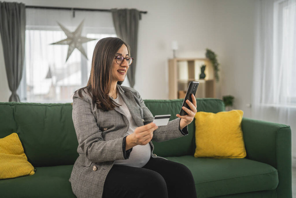 Schwangere beim Online-Einkauf hält Kreditkarte zu Hause - Foto, Bild