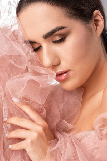 Portrait of a charming girl with delicate makeup, lush eyebrows with a cloth near the face. Eyes closed. Personal care, cosmetology and makeup concept. - Photo, Image