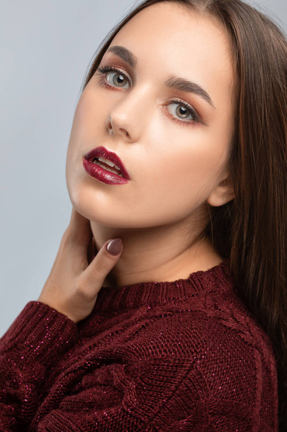 Brunette girl with beautiful makeup, with clean skin, long hair in a burgundy winter sweater. New Year concept - Photo, Image