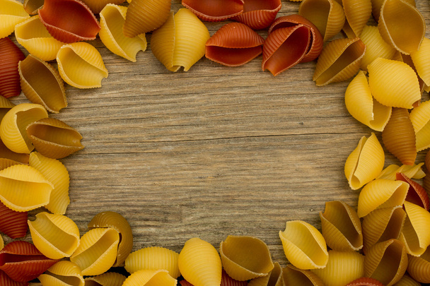 Shell pasta on wooden table top view frame - 写真・画像
