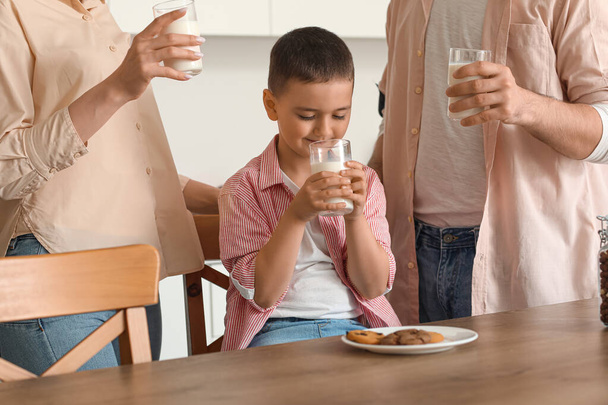 Niño pequeño con sus padres bebiendo leche en la cocina - Foto, Imagen