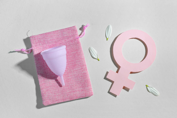 Skład z kubkiem menstruacyjnym, torbą i symbolem kobiety z papieru na szarym tle - Zdjęcie, obraz