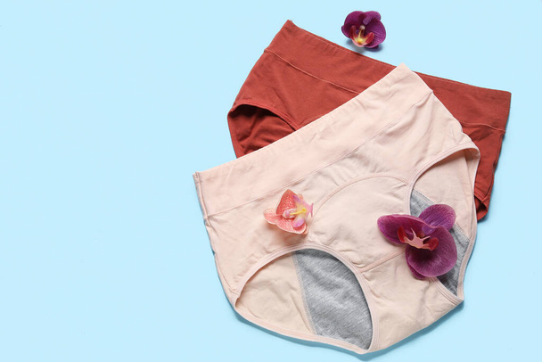 Composition with period panties and beautiful flowers on blue background - Photo, Image
