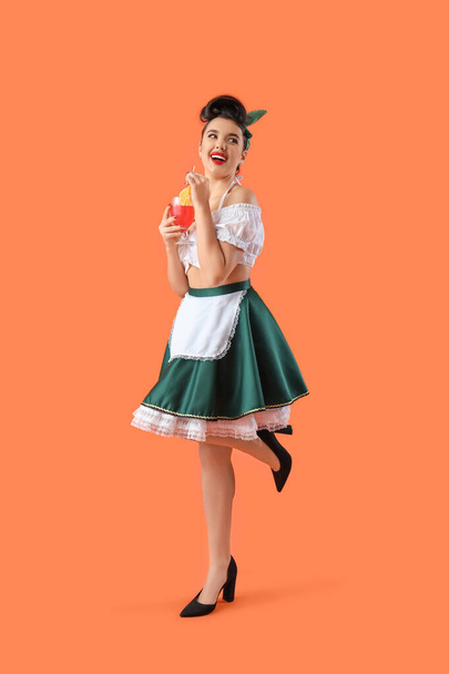 Young pin-up waitress with cocktail on orange background - Zdjęcie, obraz