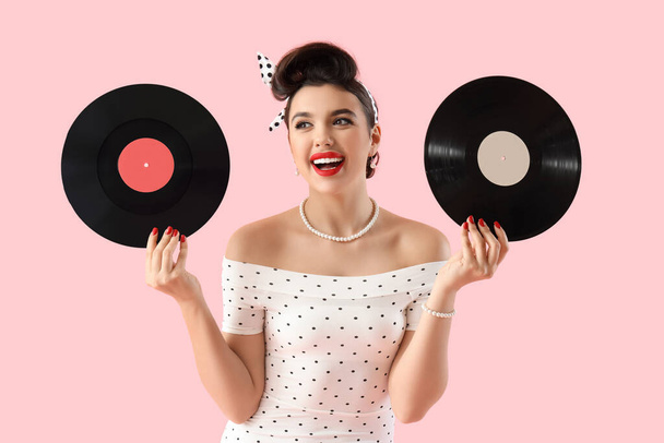 Jeune pin-up femme avec disques vinyle sur fond rose - Photo, image