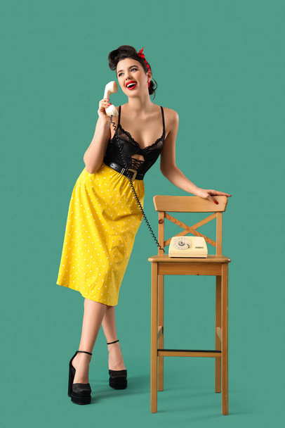Jeune pin-up femme parlant par téléphone sur fond vert - Photo, image