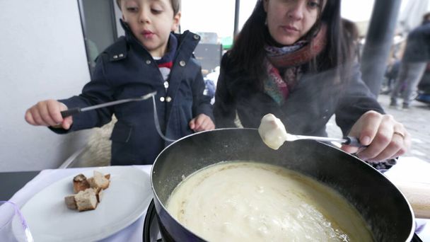 Moeder en kind Genieten van Swiss Fondue op vakantie, close-up van warme traditionele Europese gerechten in restaurant tijdens het koude winterseizoen - Foto, afbeelding