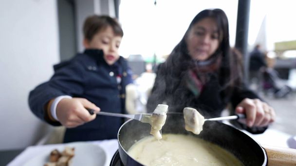 冬の休暇でスイスのフォンデュエを救う母と子供, 伝統的なヨーロッパ料理クローズアップ - 写真・画像